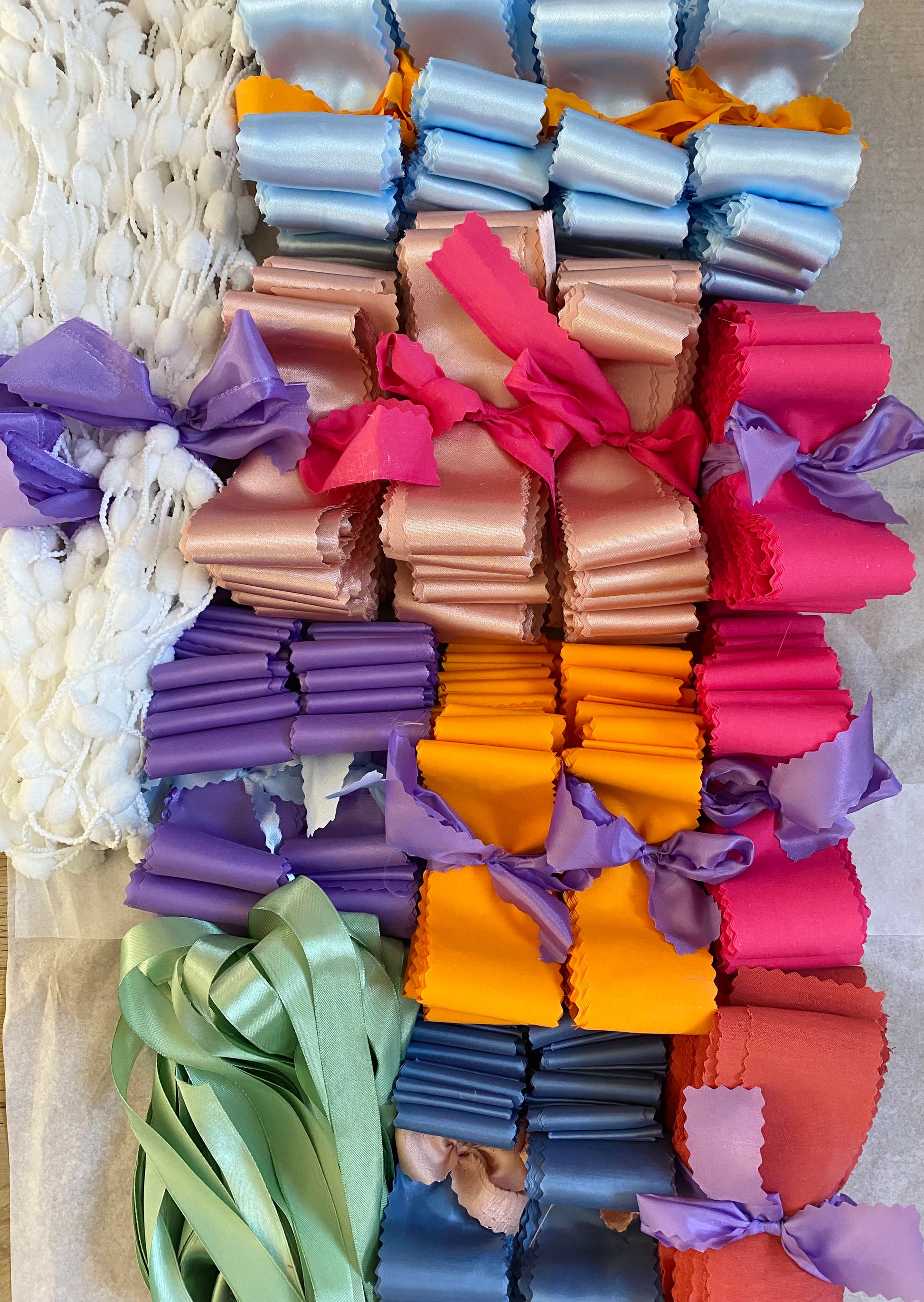 A DIY backdrop showing a colourful assortment of different fabrics cut into ribbon strips and bundled together into coordinating colours. 
