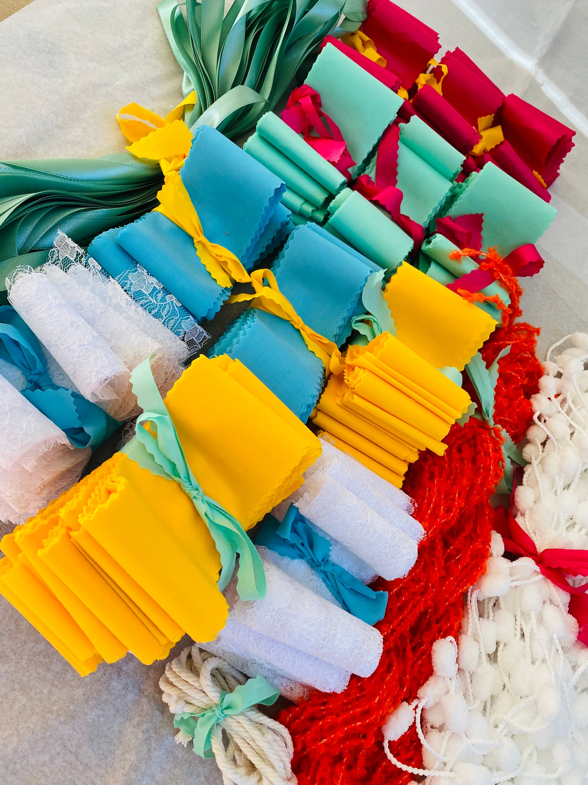 A DIY backdrop kit shown as a large quantity of colourful strips of fabric neatly folded and tied together in colour coordinated bundles. 