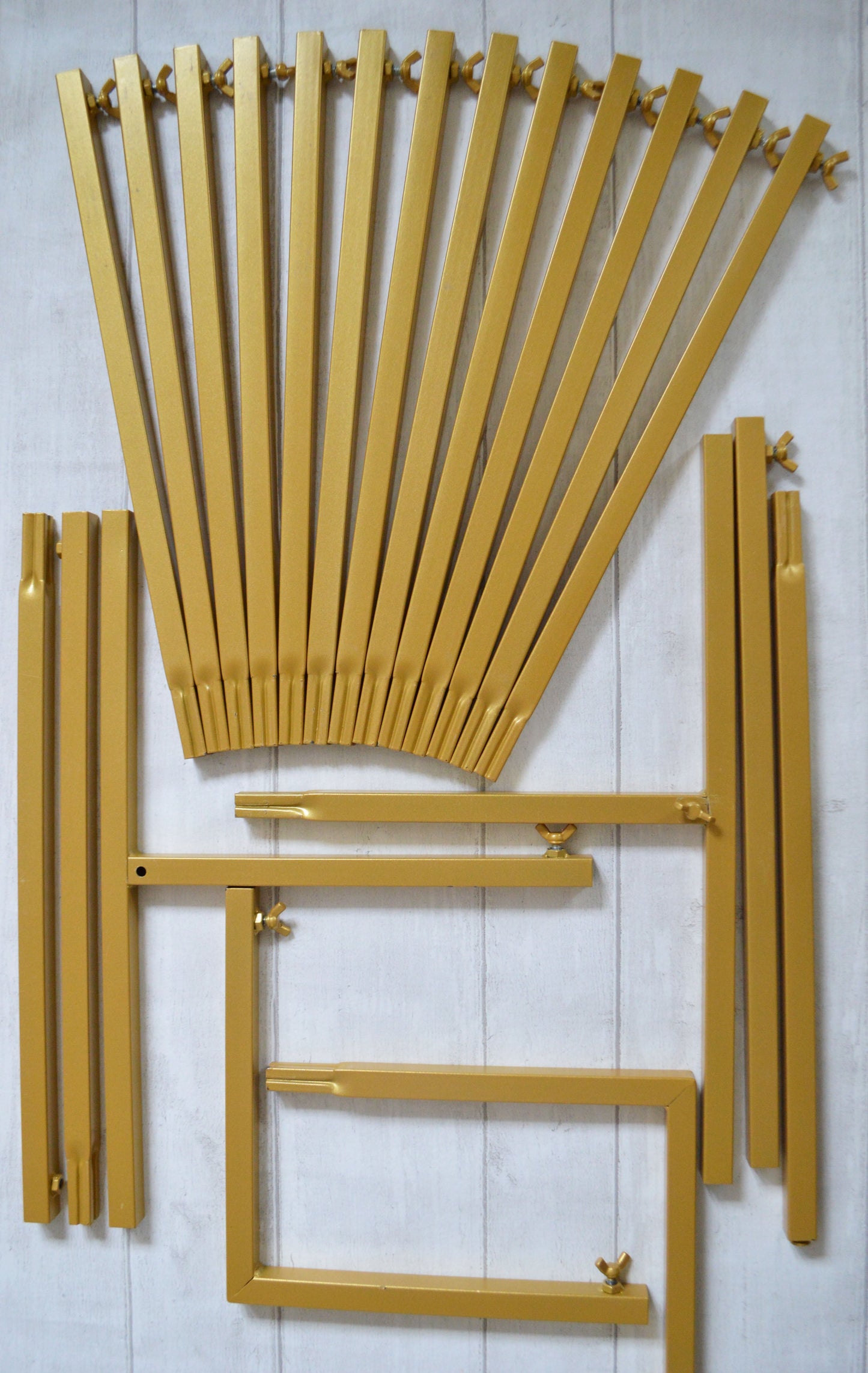 Flat lay of gold metal bars and wing nuts which will for a backdrop stand when constructed