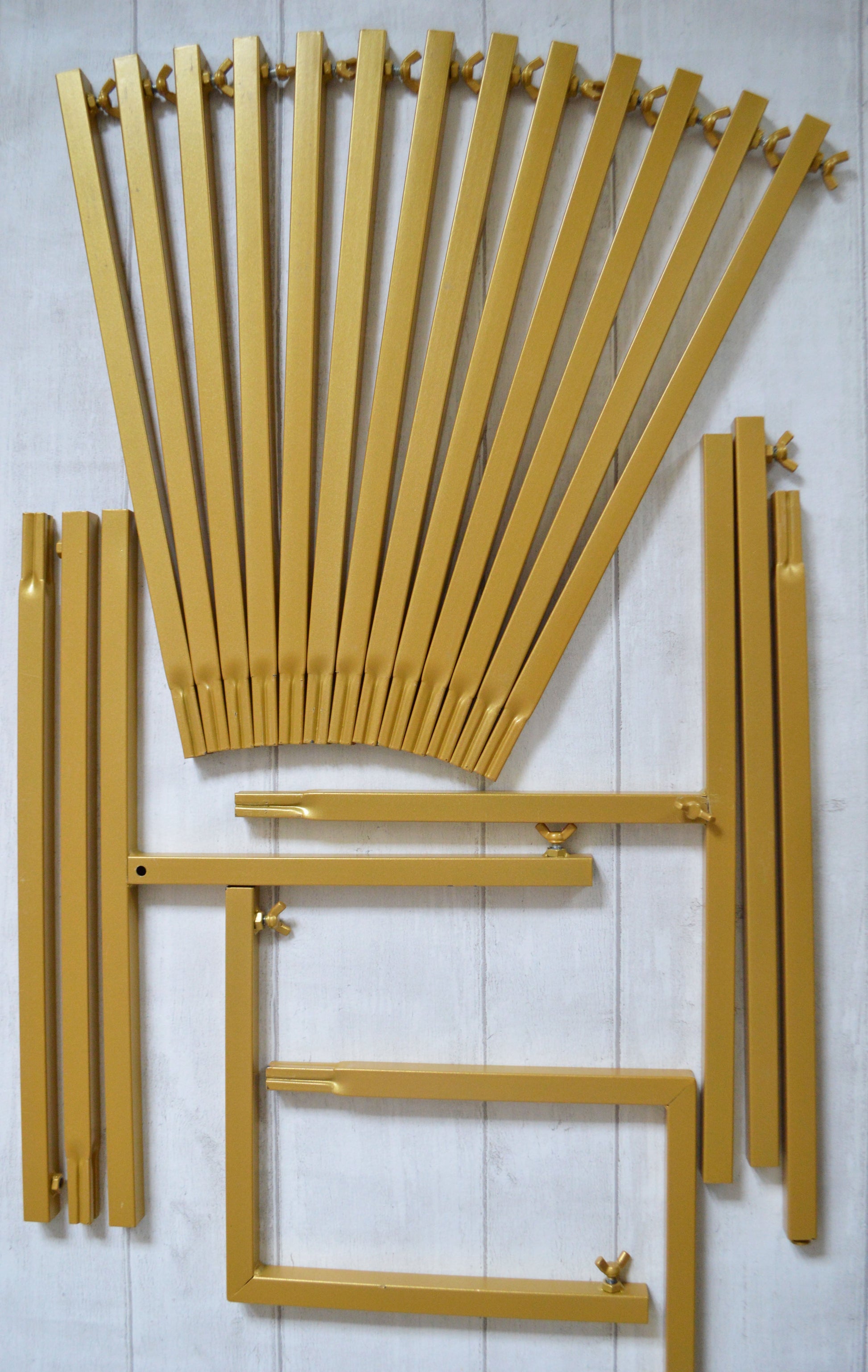 Flat lay of gold metal bars and wing nuts which will for a backdrop stand when constructed