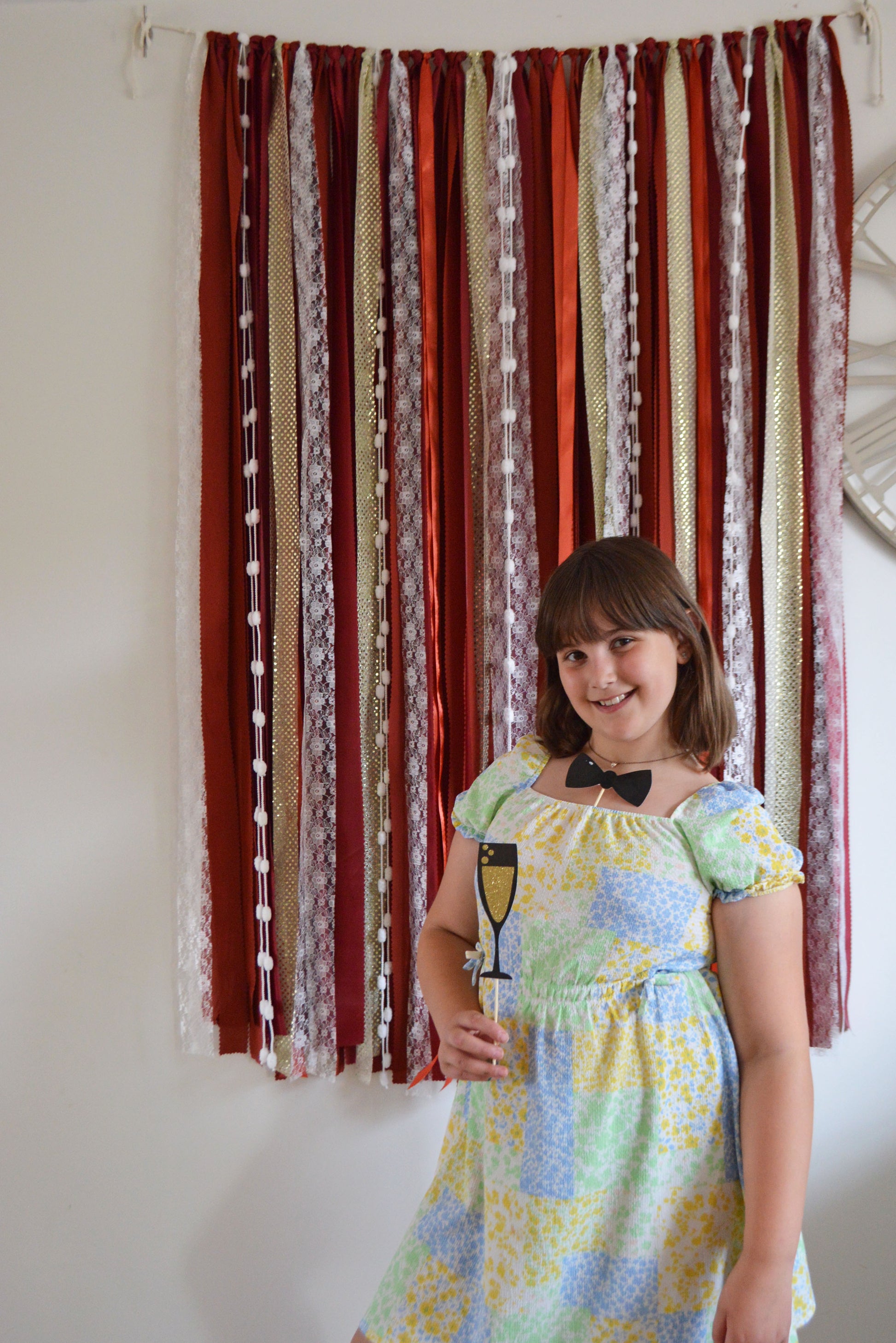 Woman in a colorful dress standing in front of a striped curtain