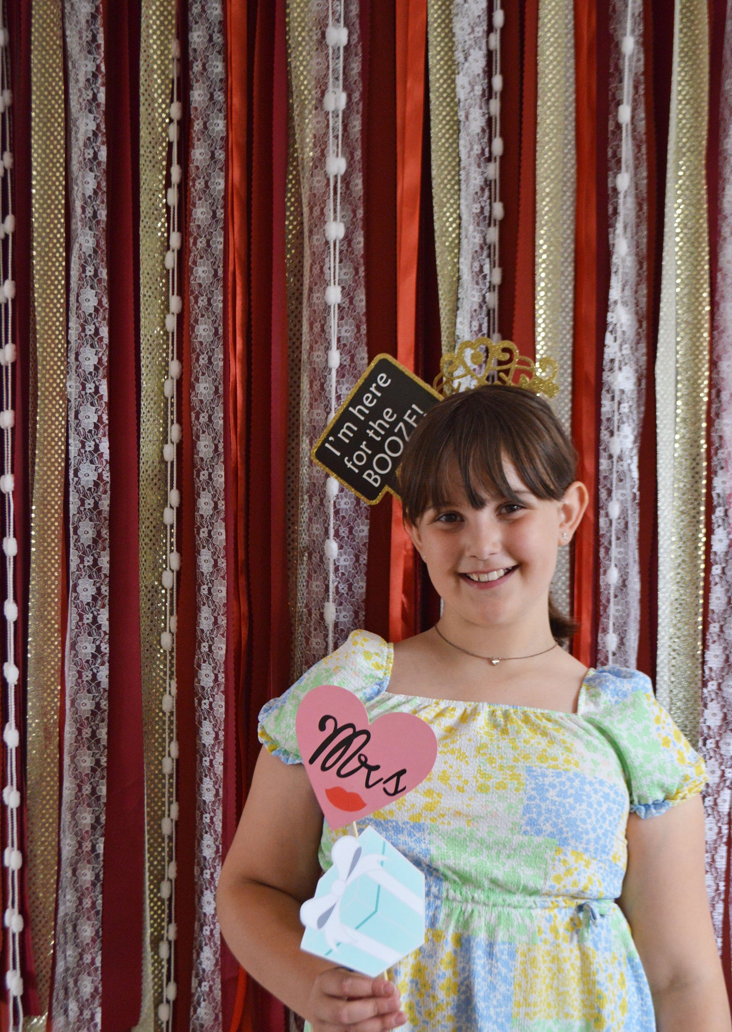 Young girl in a colorful dress with props in front of patterned curtains